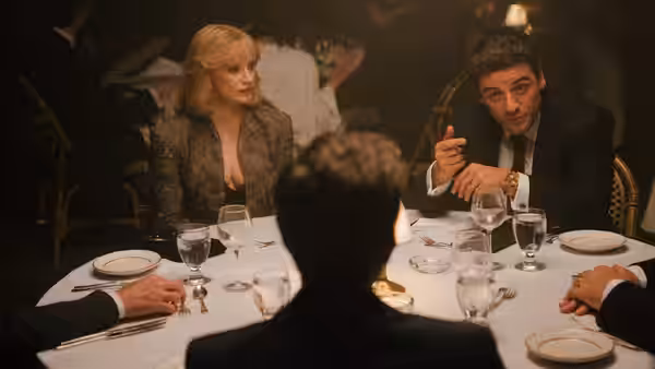 Anna Morales (Jessica Chastain) and Abel Morales (Oscar Isaac) sit at a formal dinner table