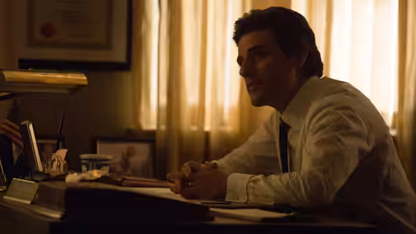 Abel Morales (Oscar Isaac) sits at his desk with hands clasped looking aside