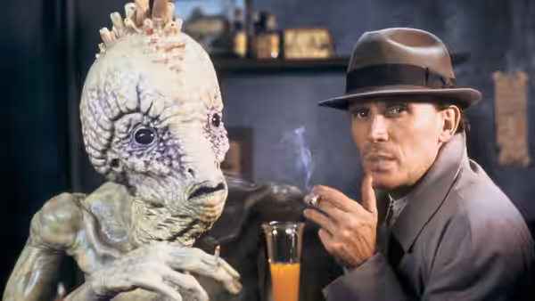 Bill Lee (Peter Weller) smoking beside a large creature at a table