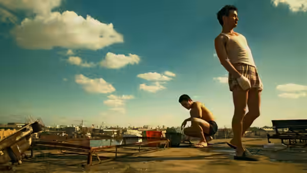 Two men on a rooftop one standing one crouching