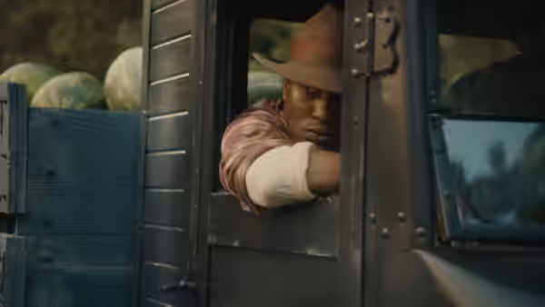 A man leans from the window of a truck loaded with watermelons