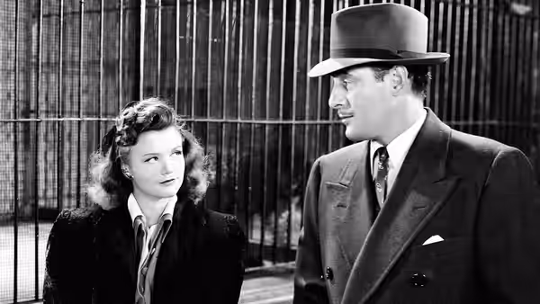 Alice Moore and Oliver Reed stand together before a tall metal fence