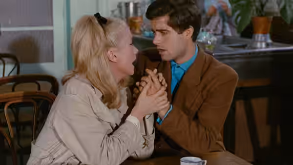 Geneviève and Guy hold hands across a table in a café