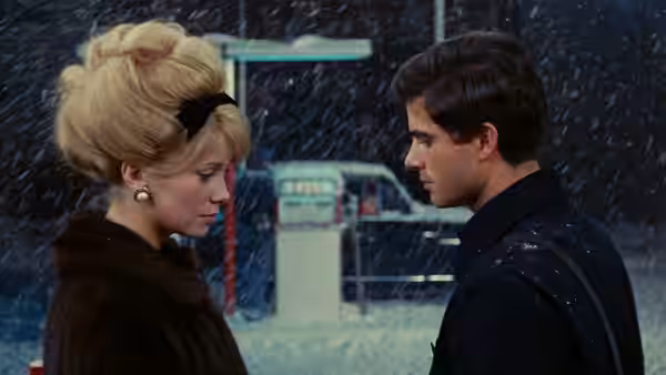 Madeleine and Guy face each other outside a brightly lit shop
