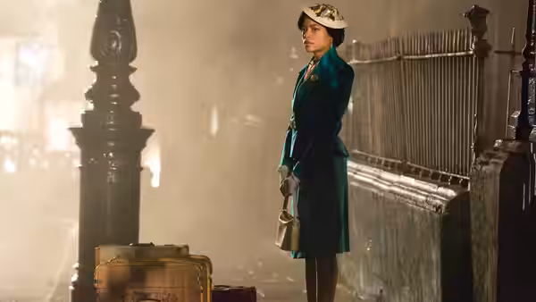 Hortense (Naomie Harris) stands beside her suitcase on a station platform