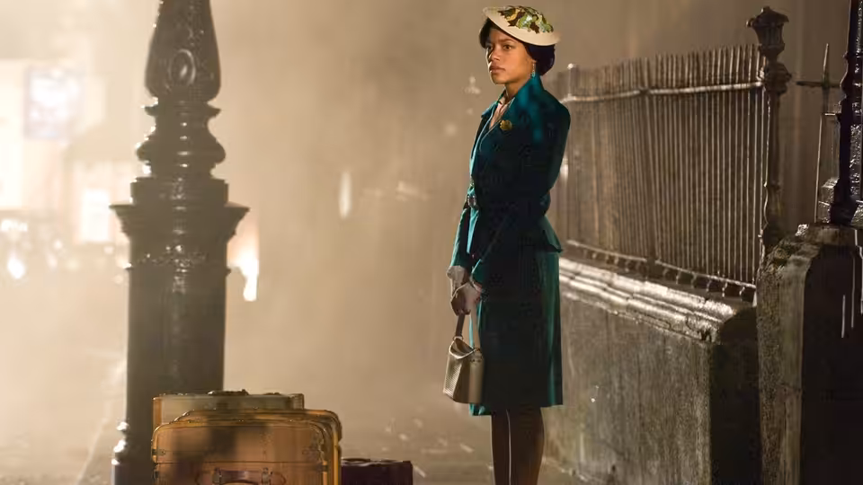 Hortense (Naomie Harris) stands beside her suitcase on a station platform