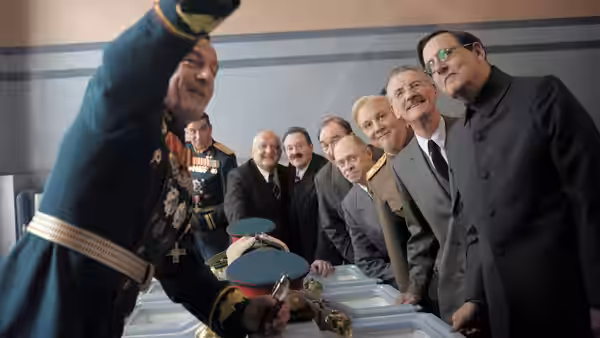Men gather around an open casket as one salutes in a hall