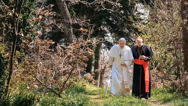 Pope Benedict XVI (Anthony Hopkins) walks through a wooded garden with Cardinal Bergoglio (Jonathan Pryce)