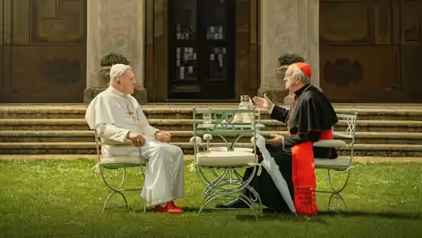 Pope Benedict XVI (Anthony Hopkins) talks with Cardinal Bergoglio (Jonathan Pryce) at a garden table
