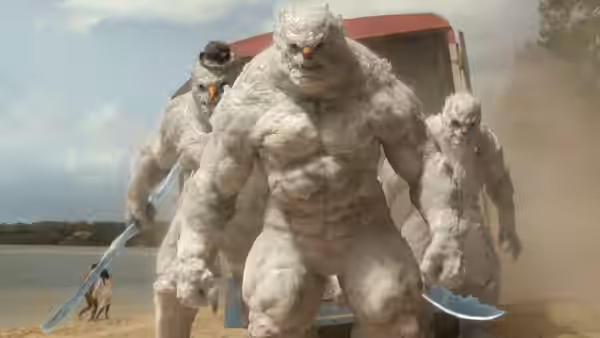 Three large white furry creatures advancing on a sandy beach near a truck