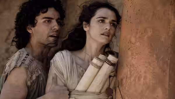 Davus (Max Minghella) and Hypatia (Rachel Weisz) hide behind a pillar looking fearful