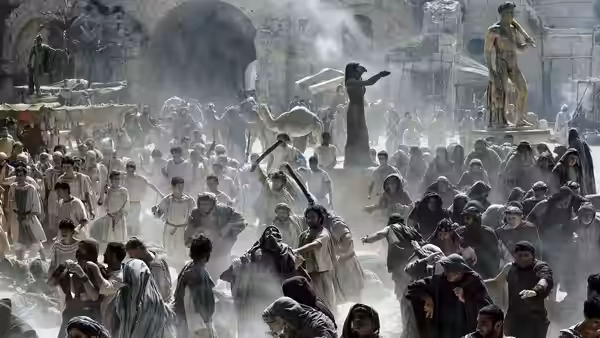 A large crowd gathers in a dusty square with a woman gesturing from a platform