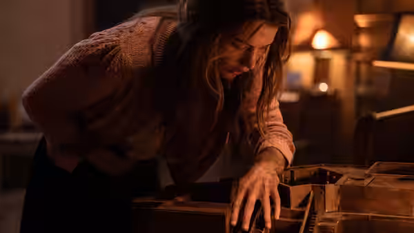Sister Paxton (Chloe East) searches inside an open wooden drawer