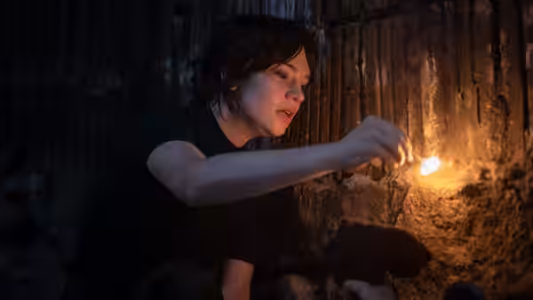 Sister Barnes (Sophie Thatcher) lights a match in a dark cellar