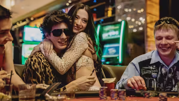 Ivan (Mark Eydelshteyn) and Ani (Mikey Madison) embracing at a casino poker table