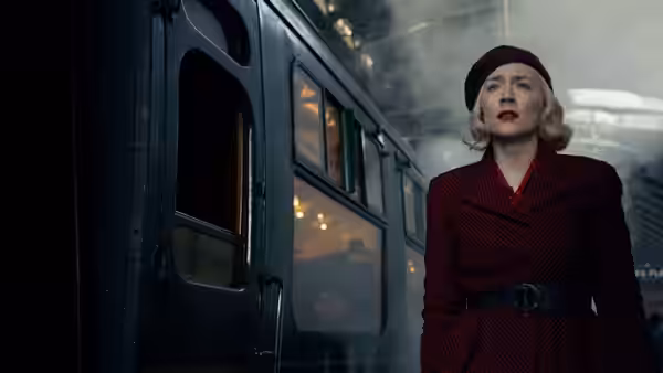 Rita (Saoirse Ronan) standing beside a steam train at a station