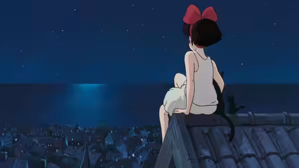 Kiki (Minami Takayama) sitting on a rooftop at night with Jiji beside her