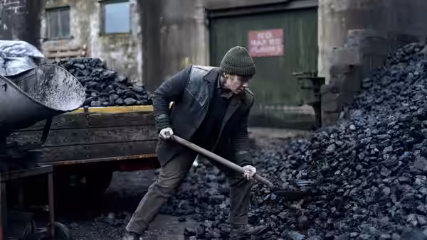 Bill Furlong (Cillian Murphy) shoveling coal beside a truck in an industrial yard