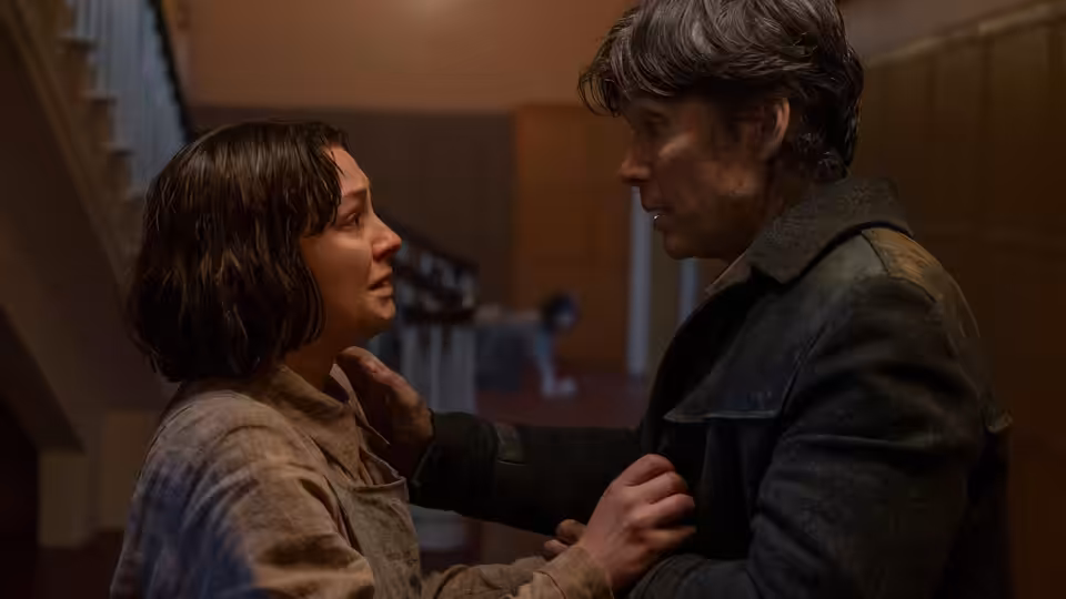Bill Furlong (Cillian Murphy) holding a young woman by the shoulders in a hallway