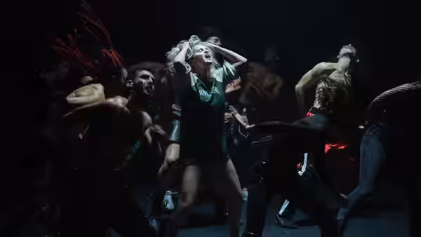 woman with green headpiece leading group of dancers in performance