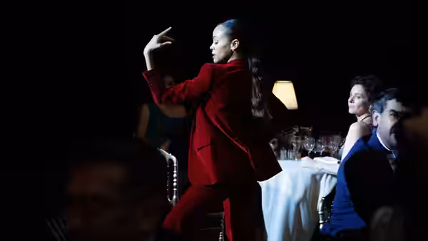woman in red suit raising arm while dancing near dinner tables