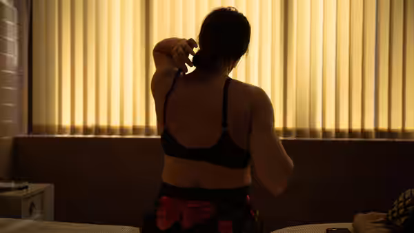woman in black bra tying hair while sitting in bedroom