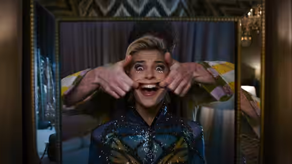 Skye Riley (Naomi Scott) pulling her cheeks in a mirror reflection