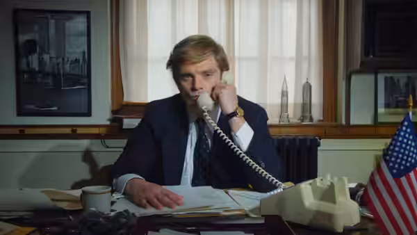 Donald Trump (Sebastian Stan) talks on the phone at his cluttered office desk