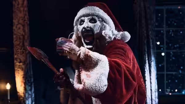 Art the Clown (David Howard Thornton) in a Santa suit raising a bloody spear