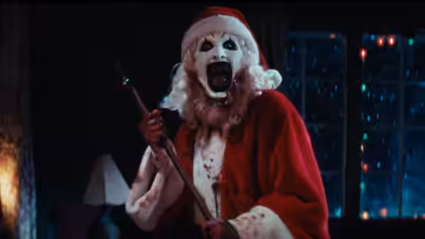 Art the Clown (David Howard Thornton) covered in blood holding a weapon in a dark room
