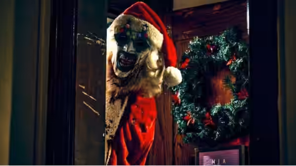 Art the Clown (David Howard Thornton) in a decayed Santa suit at a wreath-covered door