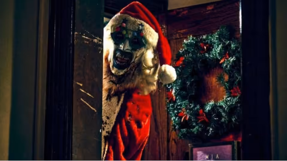 Art the Clown (David Howard Thornton) in a decayed Santa suit at a wreath-covered door