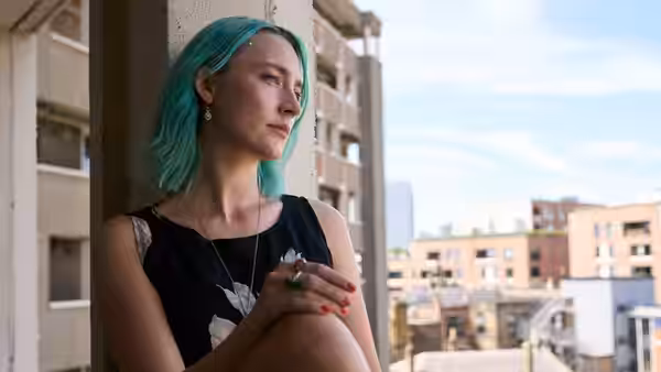 Rona (Saoirse Ronan) sits on a concrete ledge overlooking city buildings