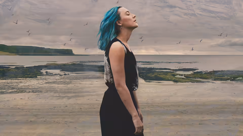 Rona (Saoirse Ronan) stands on a beach with head tilted upward