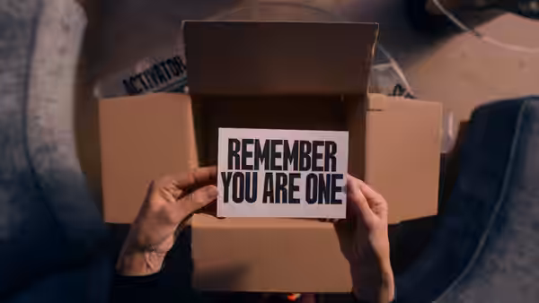 Hands holding a sign reading remember you are one inside an open box