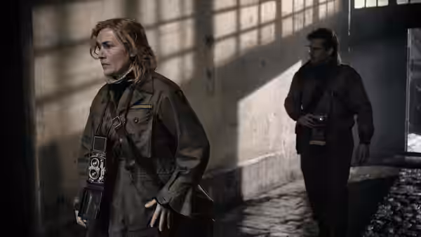 Lee Miller (Kate Winslet) standing in shaft of light inside derelict building