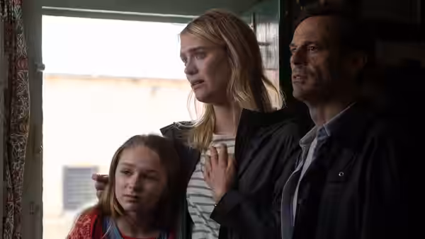 Woman and man stand with a girl looking out a window