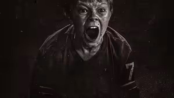 Boy in a dirty sports jersey shouts with mouth wide open