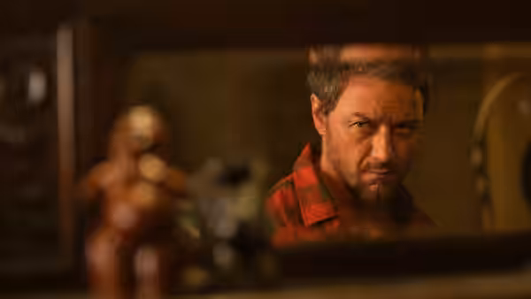 Man in a plaid shirt looks through a glass window frame
