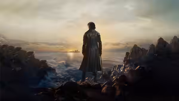 A man in a long coat stands on cliffs overlooking the sea at sunset