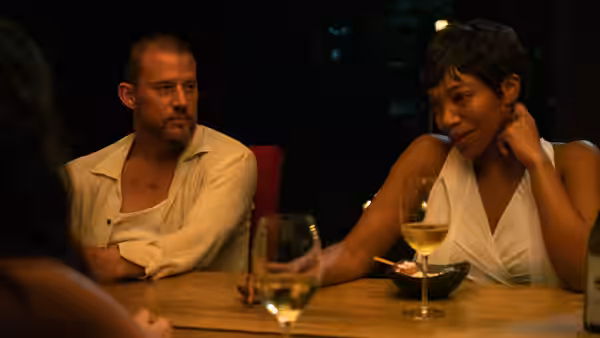 Slater (Channing Tatum) and Frida (Naomi Ackie) sit at a dinner table
