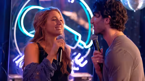 Lily Bloom (Blake Lively) and Ryle Kincaid (Justin Baldoni) singing with microphones