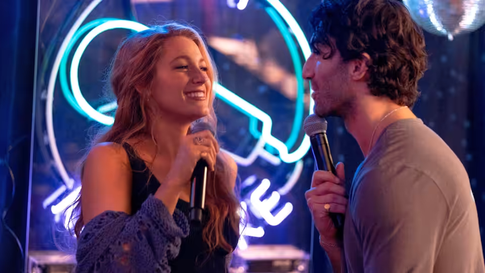 Lily Bloom (Blake Lively) and Ryle Kincaid (Justin Baldoni) singing with microphones