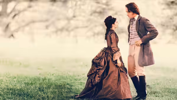 A woman and a gentleman talk together in a grassy park
