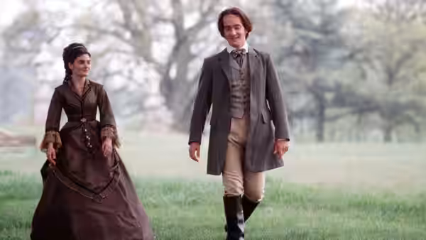 A woman and a gentleman walk together across a grassy park