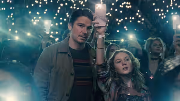 Cooper (Josh Hartnett) holding a phone beside Riley (Ariel Donoghue) in a concert crowd