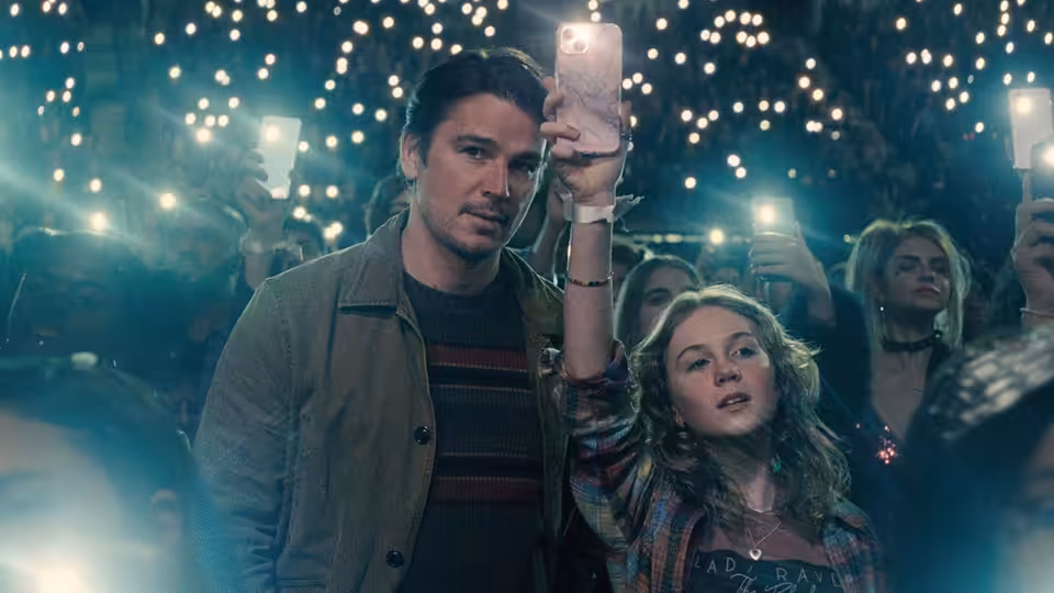 Cooper (Josh Hartnett) holding a phone beside Riley (Ariel Donoghue) in a concert crowd