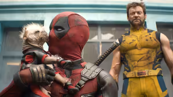 Deadpool (Ryan Reynolds) holding a small creature with Wolverine (Hugh Jackman) nearby