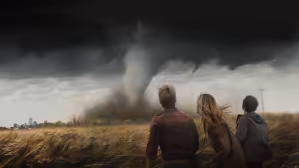 three people standing in a field watching a large tornado approach