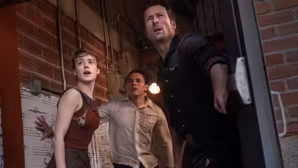 a woman and two men standing in an open doorway looking upwards